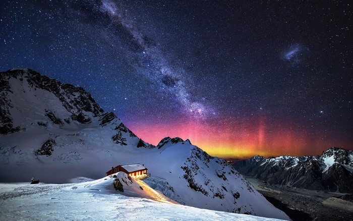 Mountain hut under the Milky Way and aurora