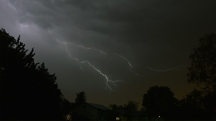 Lightning storm over houses and trees