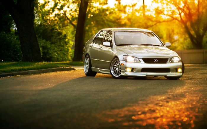 Silver Lexus IS300 parked on a tree-lined street at sunset
