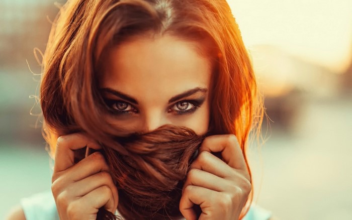 Woman with red hair covering face with hair