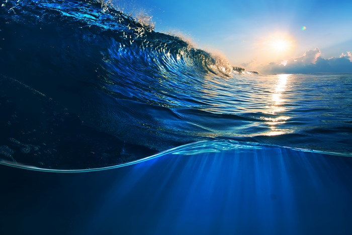 Ocean wave breaking at sunset with underwater view