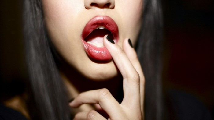 Close-up of a woman's lips with a finger inside