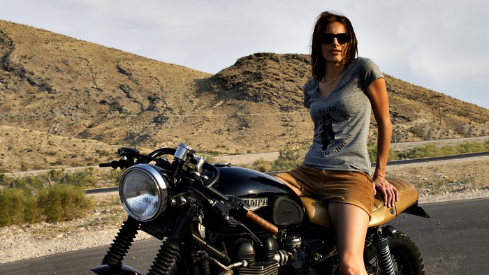 Woman on a cafe racer motorcycle in desert landscape