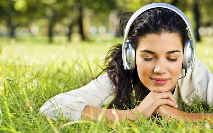Woman with headphones lying in grass