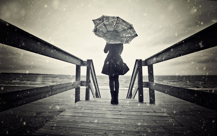 Woman with umbrella on a pier in the rain