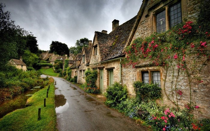 Stone cottages with climbing roses along a wet street in England