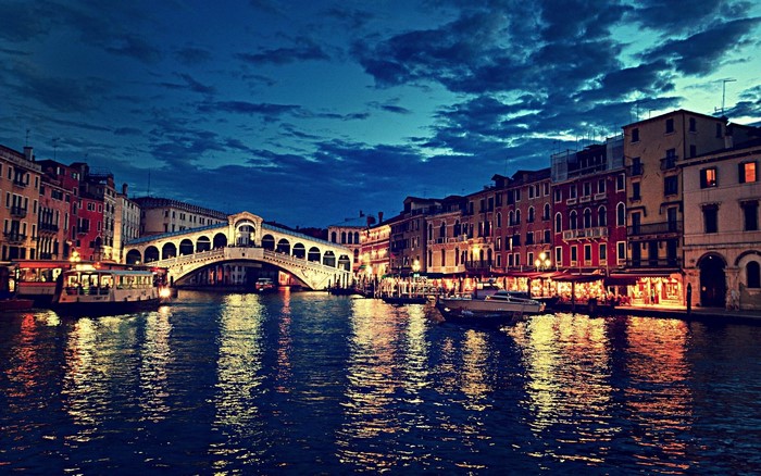 Rialto Bridge in Venice at night with canal and boats