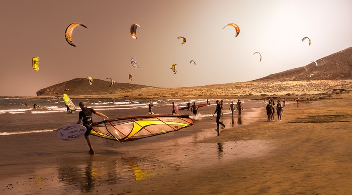 Kite surfers on a beach with a mountain in the background