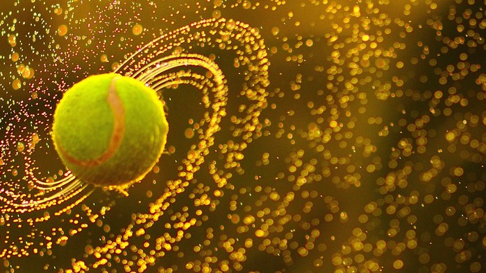 Tennis ball with water drops in motion