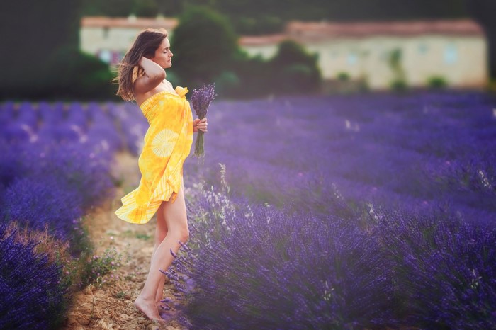 Woman in yellow dress holding lavender in a field