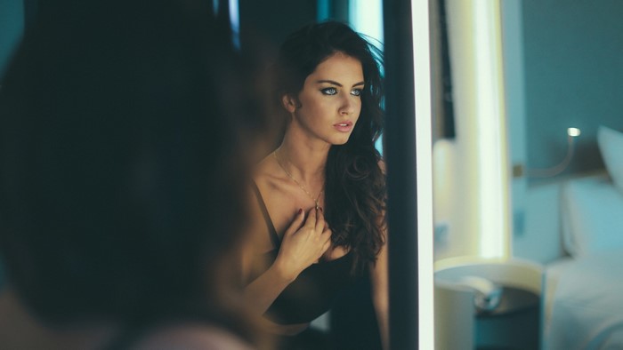 Aurela Skandaj in black dress looking in mirror