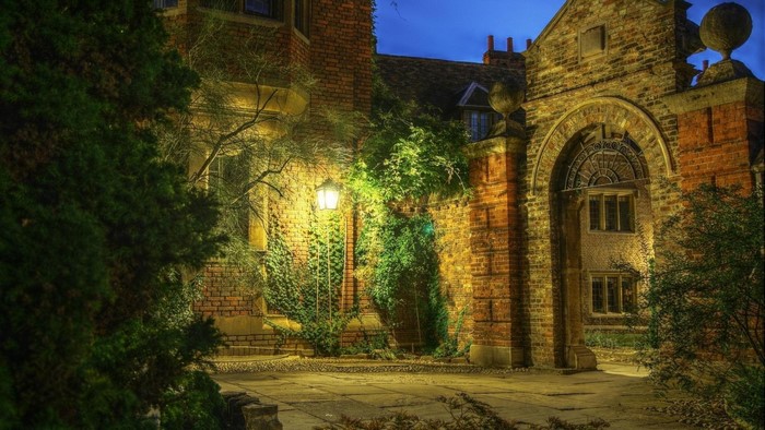 Old brick building with archway and lantern at dusk