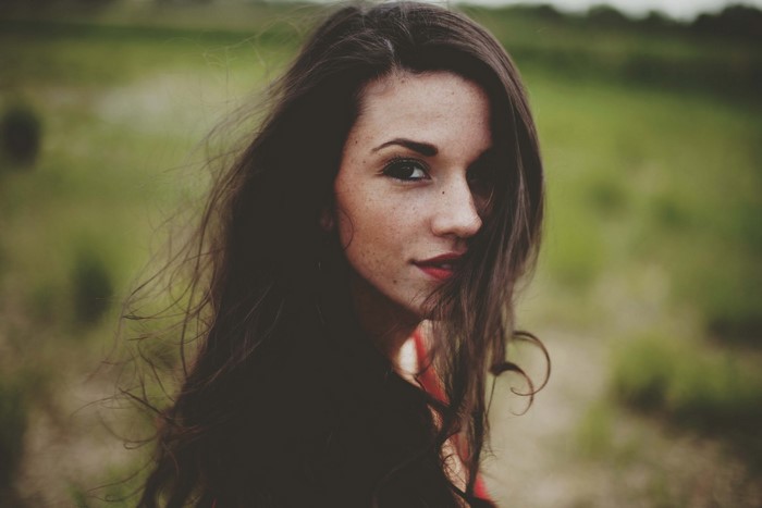Woman with long dark hair and freckles outdoors