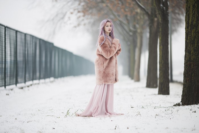 Woman with pink hair in a pink coat in the snow