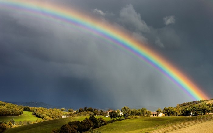 Rainbow over rolling hills and stormy clouds