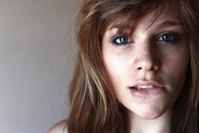 Woman with blue eyes and freckles biting her lip