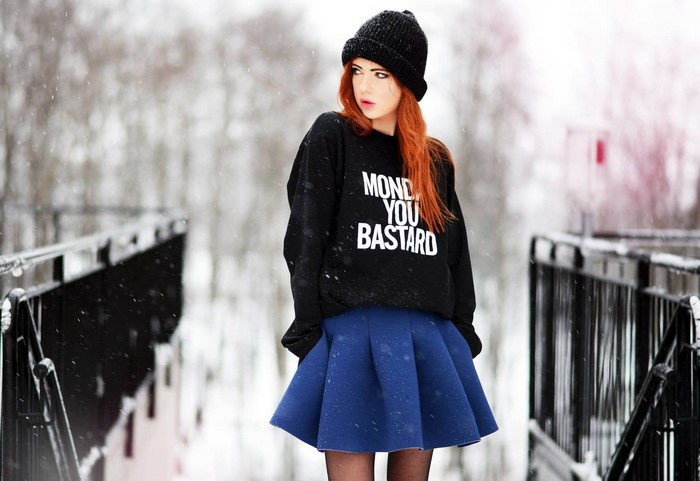 Woman with red hair wearing a black beanie and sweatshirt