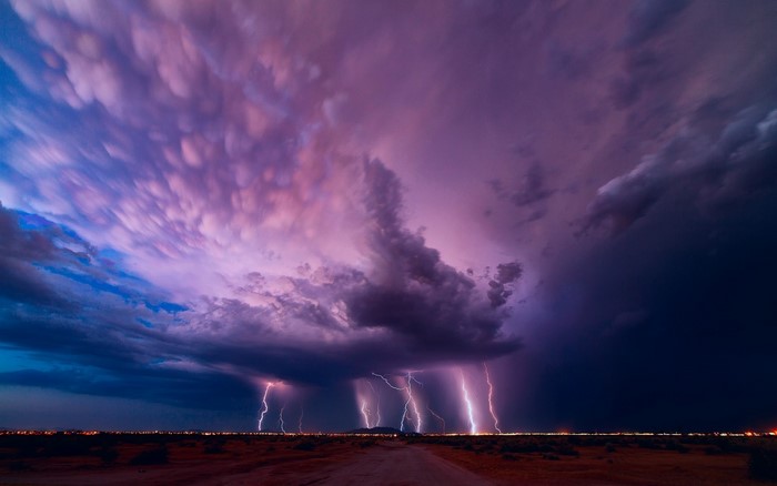 Lightning strikes over a desert landscape at dusk