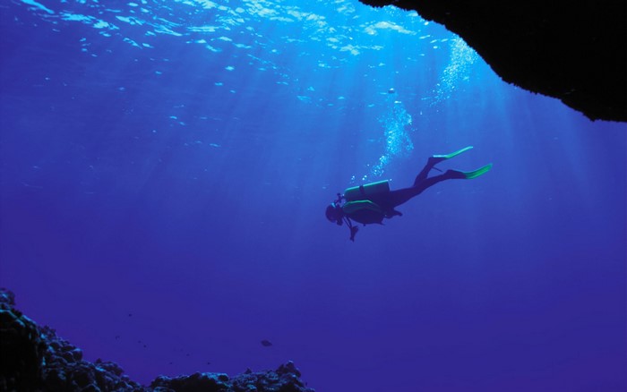 Scuba diver swimming in deep blue ocean water