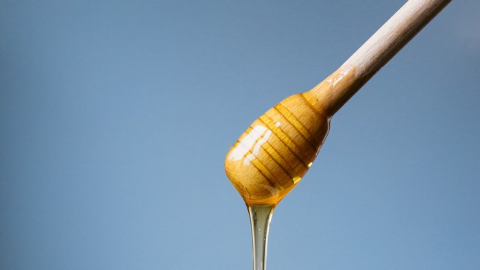 Honey dripping from a wooden honey dipper