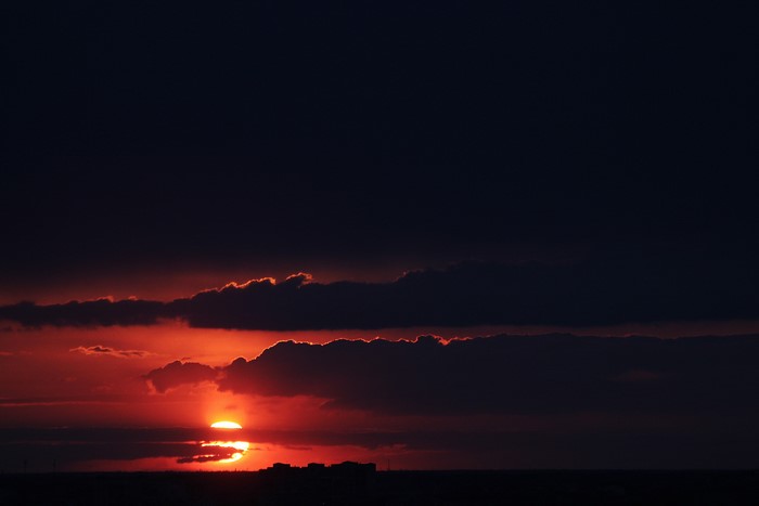 Sunset over a dark landscape with clouds