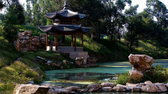 Asian architecture pagoda by a lake with rocks and trees