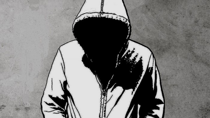 Man in a hooded jacket against a concrete wall
