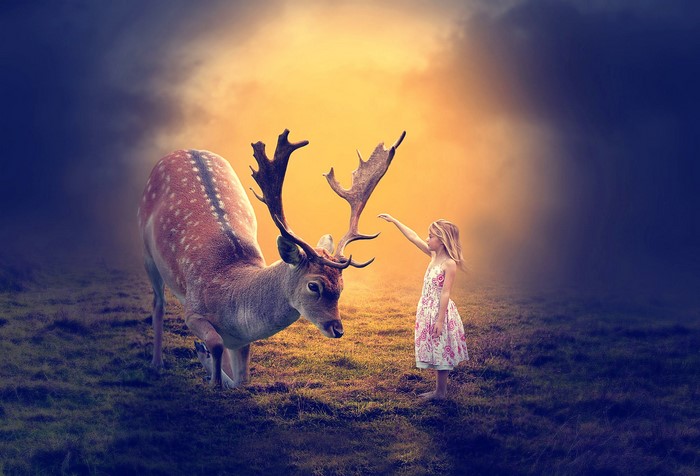 Girl reaching out to a deer in a fantasy landscape