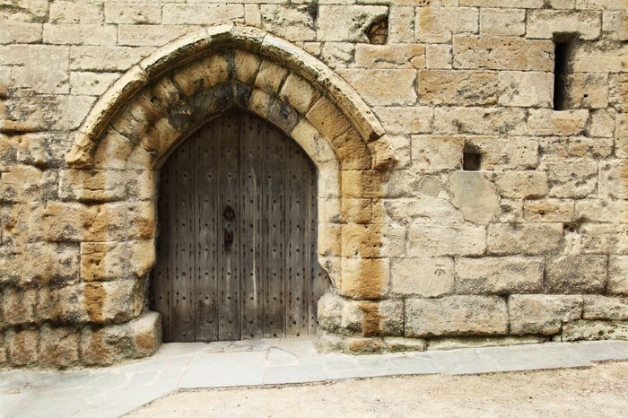 Ancient stone wall with a wooden arched doorway
