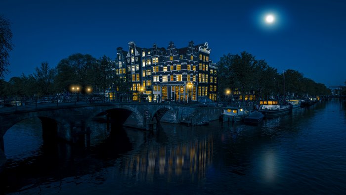 Amsterdam canal at night with moon and bridge
