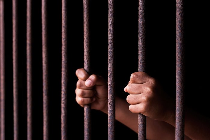 Hands gripping prison bars