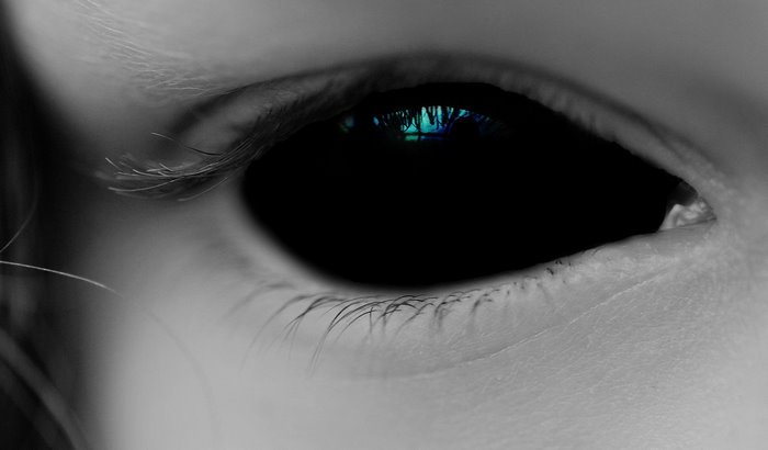 Close-up of a black demon eye with blue reflection