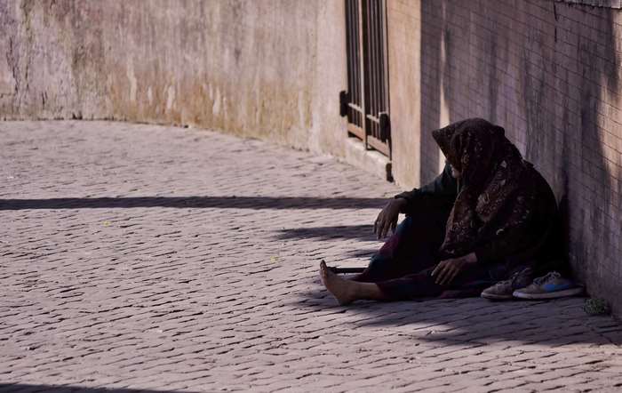 Homeless woman sitting on cobblestone street