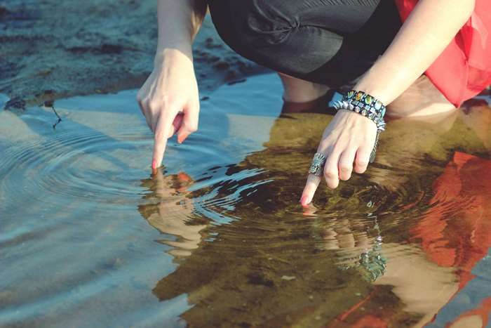 Woman's hands touching water with rings and bracelets