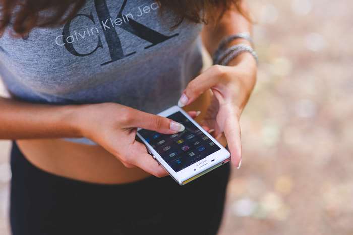Woman in Calvin Klein shirt using Sony smartphone