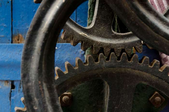 Close-up of interlocking metal gears on a blue wooden background