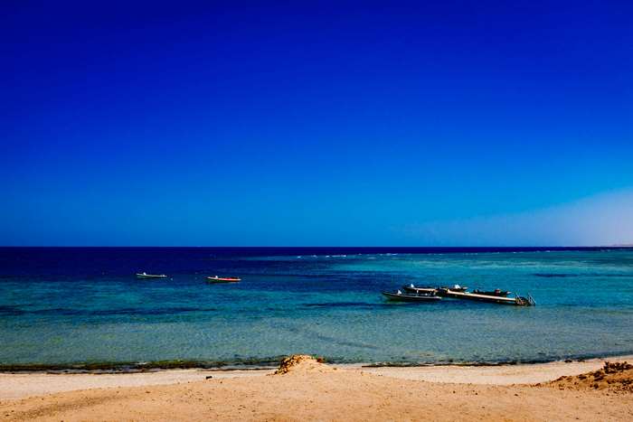 Boats on a clear blue sea near a sandy beach