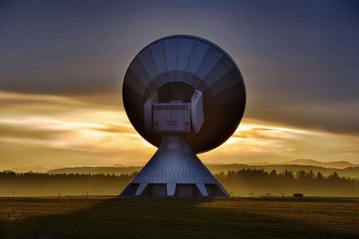 Satellite dish at sunrise over a field