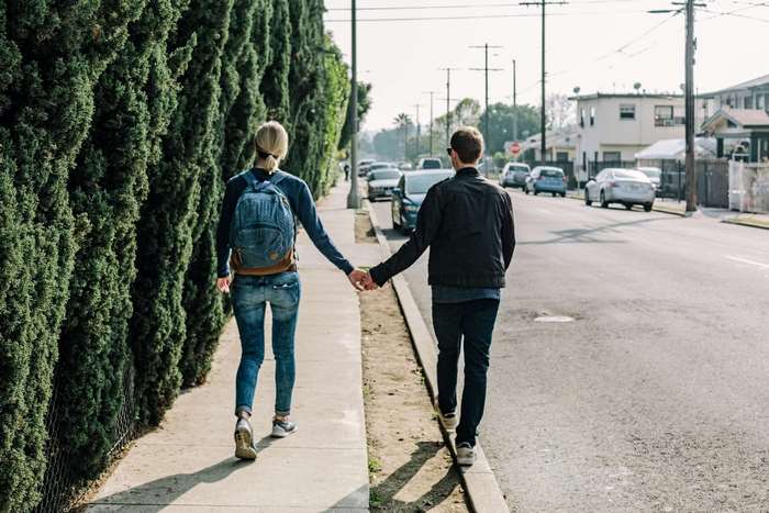 Couple Holding Hands Walking Along Quiet Street