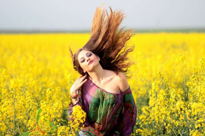 Woman with long hair in a field of yellow flowers