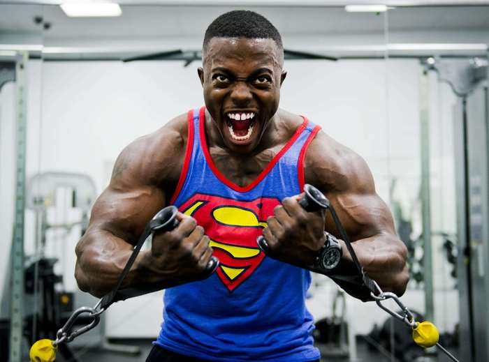 Man in Superman shirt doing cable crossovers