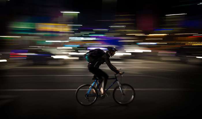 Cyclist on a road at night with light trails