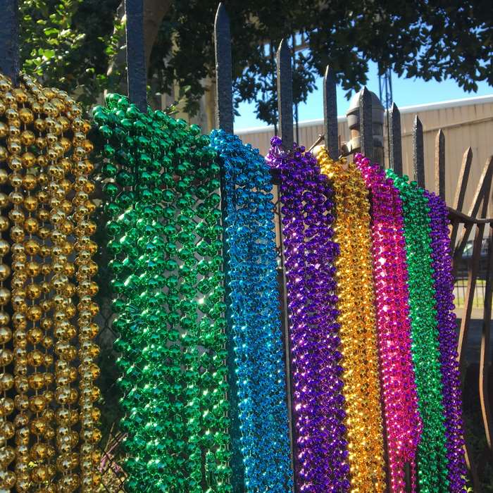 Colorful Mardi Gras beads hanging on a fence