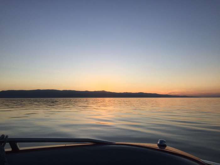 Boat on calm water at sunset with mountain horizon