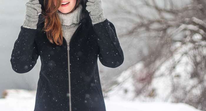 Woman in a black coat and grey sweater in the snow
