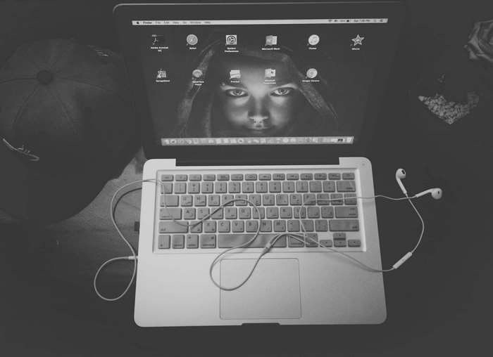 Apple laptop with headphones and a cap