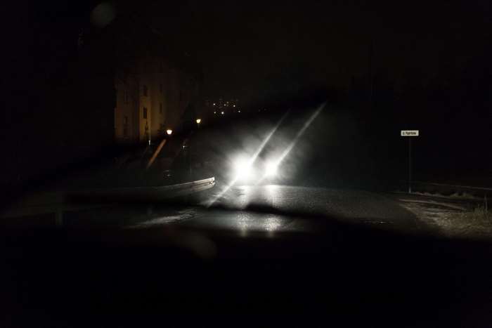 Car headlights on a dark, wet road at night