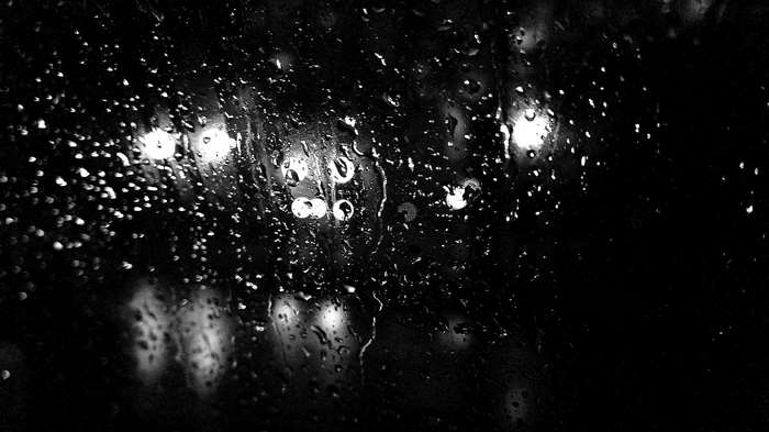 Raindrops on glass with blurred lights at night