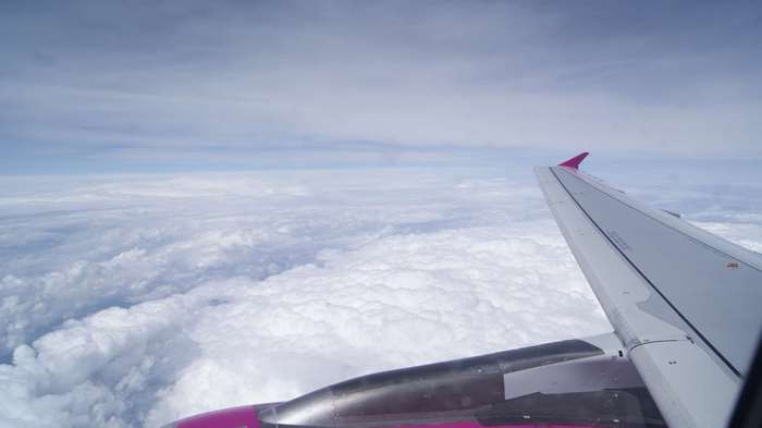 Airplane wing flying over clouds