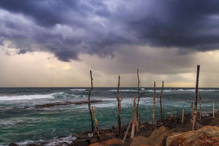 Stilt fishermen on the coast of Sri Lanka during a storm